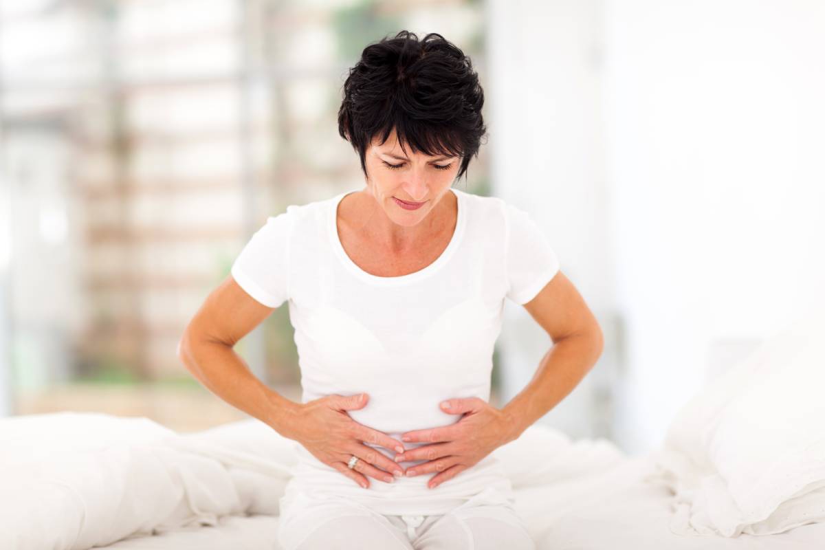 Woman experiencing abdominal pain, one of the common signs of C. diff infection.